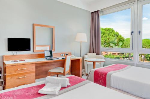 a hotel room with two beds and a desk and a window at Italiana Hotels Florence in Florence