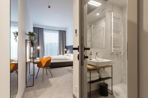 a bathroom with a sink and a bedroom with a bed at Platinum Hotel&Residence Wilanów in Warsaw