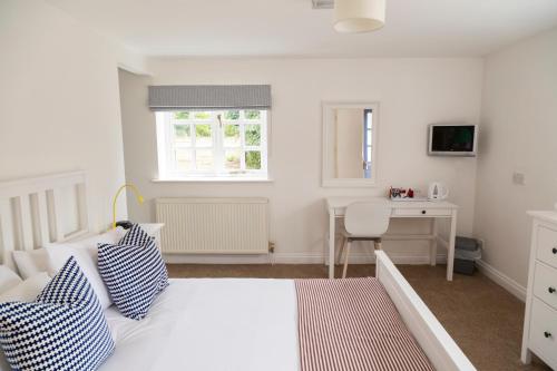 ein weißes Schlafzimmer mit einem Bett und einem Schreibtisch in der Unterkunft Five Bells Inn, Wrentham in Wrentham