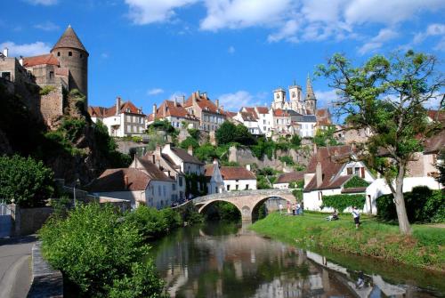 a river in a town with a bridge and buildings at Hôtel du Commerce in Semur-en-Auxois