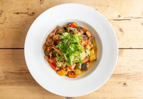 a white bowl filled with food on a wooden table at Five Bells Inn, Wrentham in Wrentham