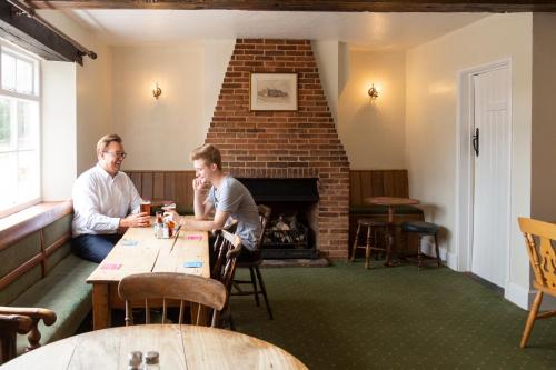 two men sitting at a table in a room with a fireplace at Five Bells Inn, Wrentham in Wrentham