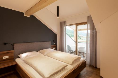 a bedroom with a bed and a large window at Mederle Hof in Appiano sulla Strada del Vino
