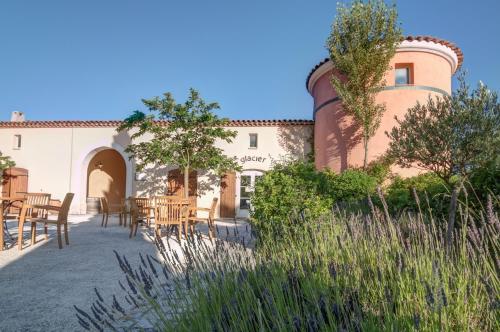 a patio with tables and chairs in front of a building at Village Pierre & Vacances Le Rouret in Grospierres