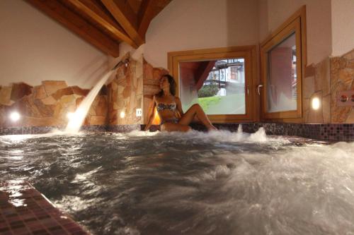 a woman in a bathing suit sitting in a hot tub at Hotel Residence Dahu in Passo del Tonale