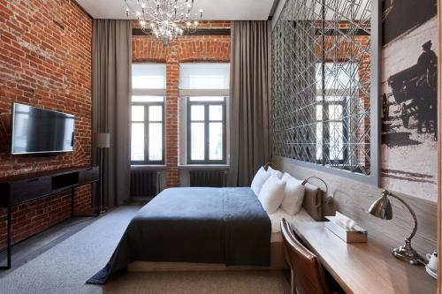 a bedroom with a bed and a tv and a brick wall at PR Myasnitsky Boutique Hotel in Moscow