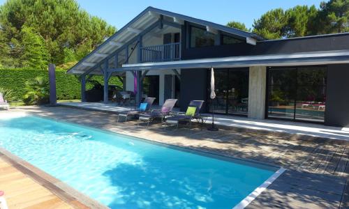 una piscina frente a una casa en Ref 111 Seignosse, Villa de standing 4 étoiles partiellement climatisée avec piscine chauffée et Wifi au calme sur terrain 1100m2 en Seignosse