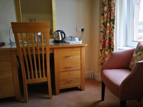 Habitación con escritorio de madera, silla y mesa. en St Ann’s Guest House, en Inverness