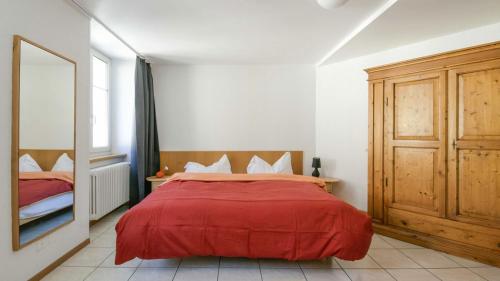 - une chambre avec un lit rouge et un miroir dans l'établissement Chez Gilles hôtel resto bar SA, à La Chaux-de-Fonds