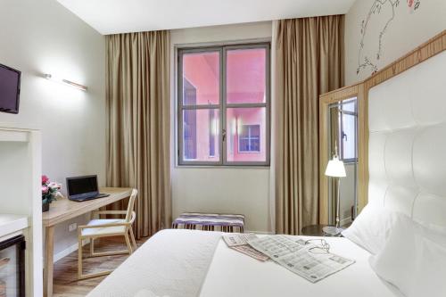 a hotel room with a bed and a desk and a window at Italiana Hotels Milan Rho Fair in Rho
