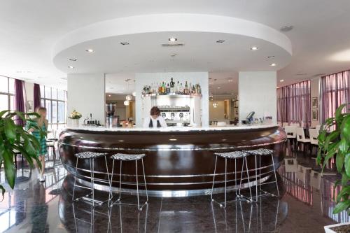 a bar in a restaurant with a woman behind the counter at Italiana Hotels Milan Rho Fair in Rho