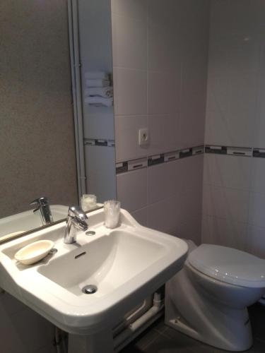 une salle de bain avec un lavabo blanc et des toilettes dans l'établissement Hôtel La Tour D'Auvergne, à Pont-lʼAbbé
