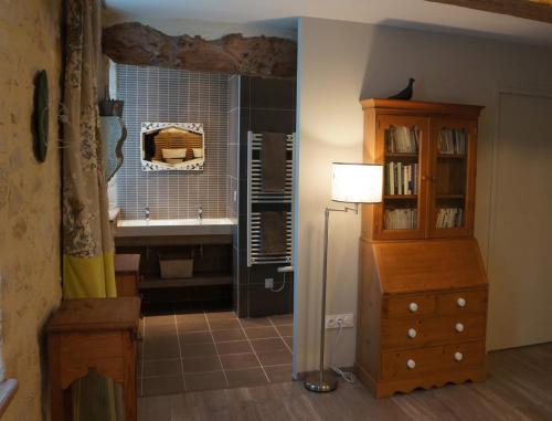 La salle de bains est pourvue d'un lavabo, d'une commode et d'une lampe. dans l'établissement B&B Les Oiseaux de Passage, à Isigny-sur-Mer