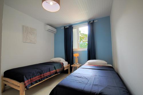 Cette chambre comprend 2 lits dans une chambre dotée de murs bleus et d'une fenêtre. dans l'établissement Villa with private pool MQDI53, au Diamant