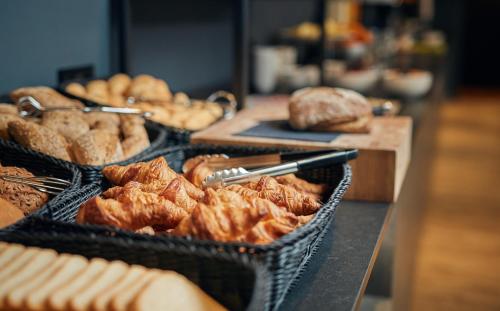 a counter with baskets of bread and pastries at Inntel Hotels Amsterdam Centre in Amsterdam