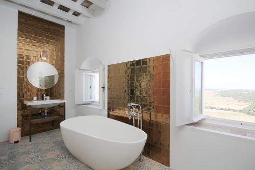 a bathroom with a large white tub and a window at Casa Bonhomía in Vejer de la Frontera