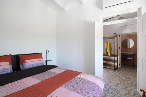 a bedroom with a bed and a hallway with a mirror at Casa Bonhomía in Vejer de la Frontera