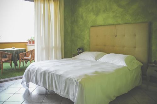 a bedroom with a large white bed with a green wall at Locanda Belvedere in Saludecio