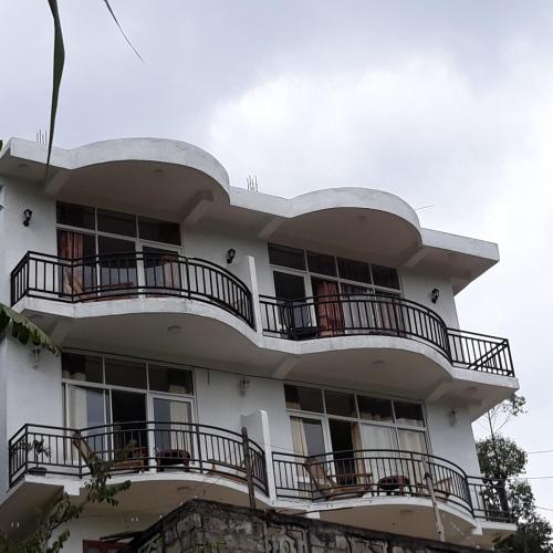 a white building with balconies on top of it at Lilly Guest Inn in Haputale