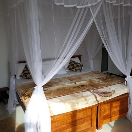 a bedroom with a canopy bed with white curtains at Lilly Guest Inn in Haputale