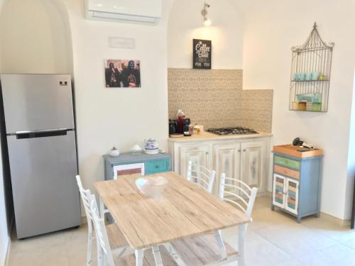 a kitchen with a wooden table and a refrigerator at Ogliastra Luxury Apartment - AJPSARDINIA in Tortolì