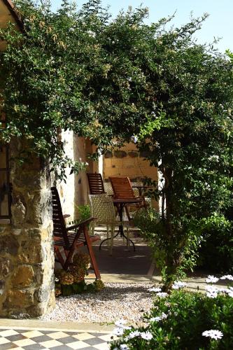 a patio with chairs and a table under a tree at Hotel Maison Tresnuraghes in Tresnuraghes