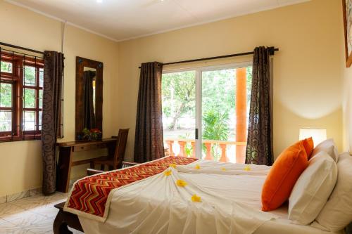 a bedroom with a large bed and a window at Villas des Alizes beachfront suites and garden villas in Grand'Anse Praslin