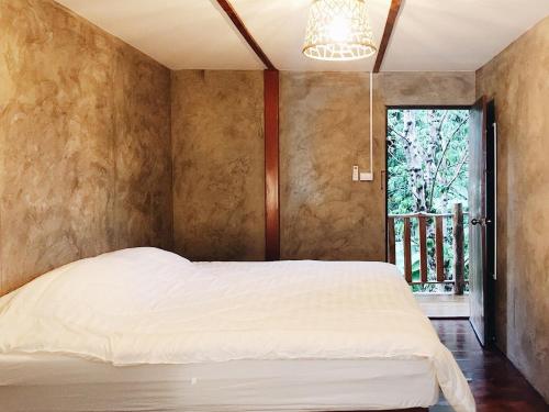 a bedroom with a white bed and a window at Petit Paramata in Phitsanulok