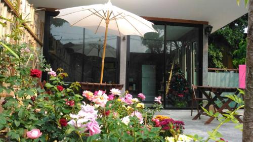 a patio with an umbrella and some flowers at Petit Paramata in Phitsanulok