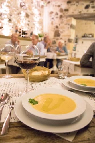 a table with a plate of soup and a glass of wine at Hotel Maison Tresnuraghes in Tresnuraghes