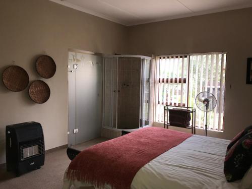 a bedroom with a large bed and a window at Cheetah Lodge Guest House in Hartenbos