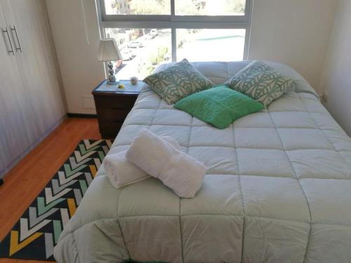 a bedroom with a large bed with pillows and a window at Estudio Vacacional in Cochabamba
