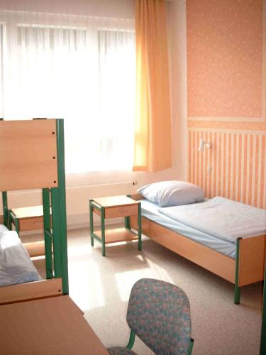 a bedroom with two beds and a chair and a window at Internationales Gästehaus in Jena