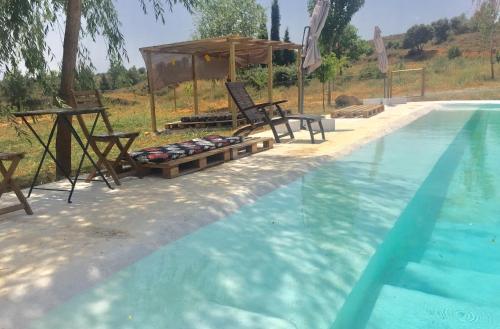 a swimming pool with a table and chairs next to it at Mas de León in Cortes de Arenoso