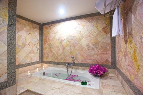 a bathroom with a bath tub with flowers in it at King Park Avenue Hotel Bangkok in Bangkok