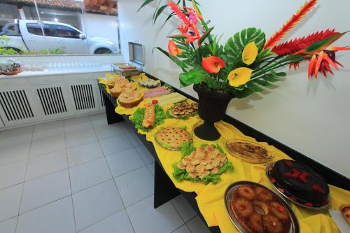 a table filled with food and a vase with flowers at Navegantes Hotel in Porto Seguro