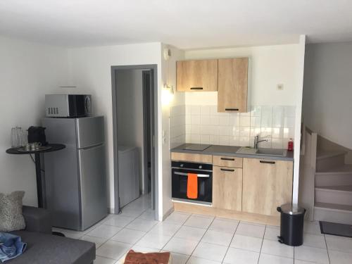 une cuisine avec des armoires en bois et un réfrigérateur en acier inoxydable dans l'établissement Résidence Village Marin Catalan, à Torreilles