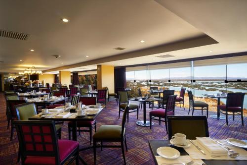 a dining room with tables and chairs and windows at GHL Hotel Lago Titicaca in Puno