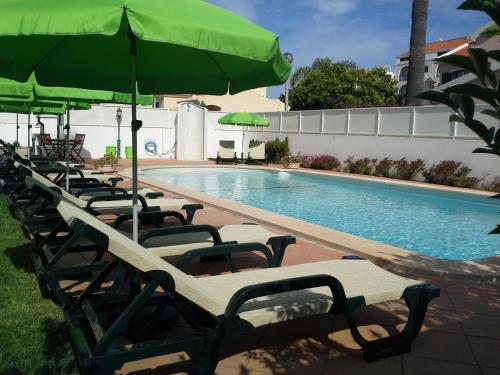 una fila de sillas con sombrillas junto a una piscina en Altura Prime - 4 Suites, Private Pool and Parking, Walk to Beach, en Altura