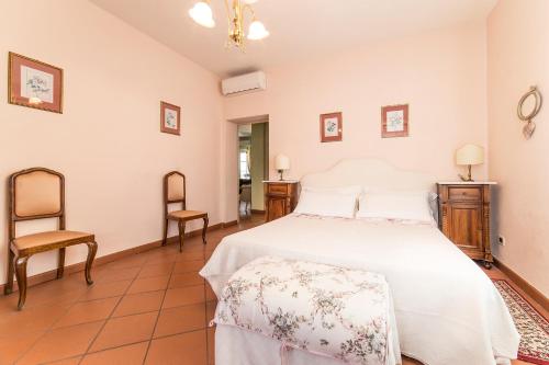 a bedroom with a white bed and a chair at Appartamento La Terrazza in Lucca