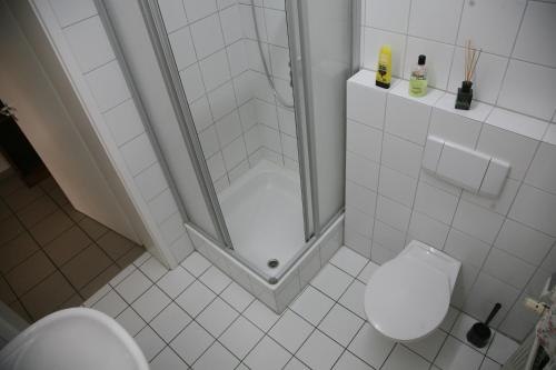 a white bathroom with a shower and a toilet at Apartmentvermietung Dortmund-Kirchhörde in Dortmund