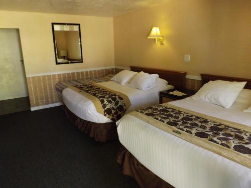 a hotel room with two beds and a mirror at Sage Motel in Vernal