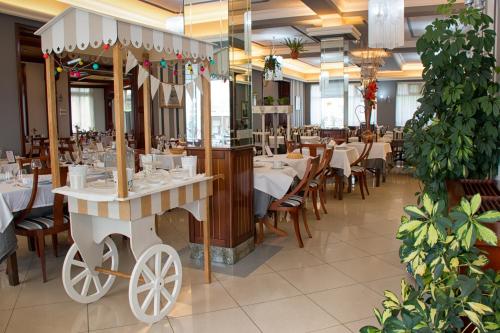 a restaurant with white tables and chairs and a cart at Hotel Arillo in Noja