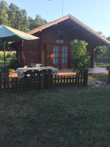 a log cabin with a table and an umbrella at Agriturismo Casale Loreto in Corchiano