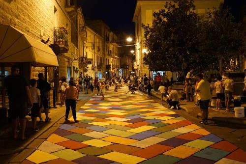 a crowd of people walking down a street with a colorful sidewalk at B&B 500 Miglia  in Tempio Pausania