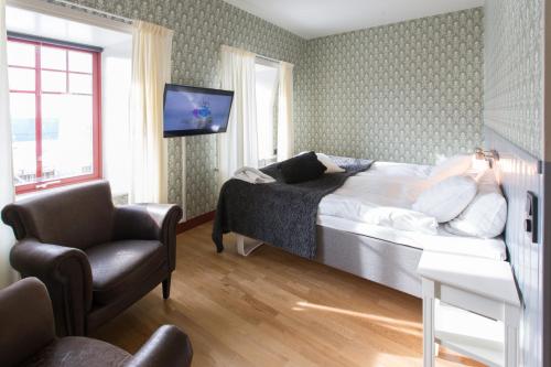 um quarto com uma cama, uma cadeira e uma televisão em Hovde Hotell em Vemdalsskalet