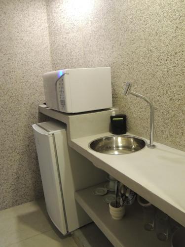 a bathroom with a sink and a microwave at Flat Camburi in Camburi