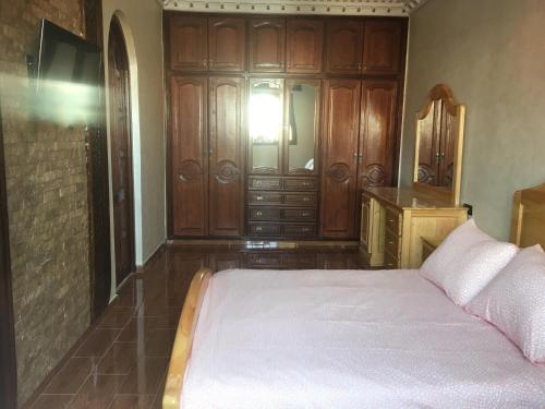 - une chambre avec un lit et une armoire en bois dans l'établissement luxury apartments, à Assilah