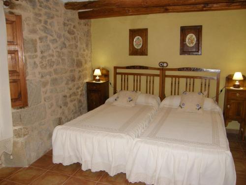 a bedroom with two beds and a stone wall at Casa rural Rosa in La Fresneda