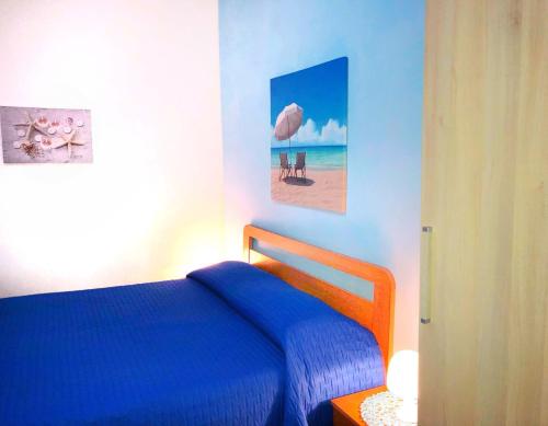 sypialnia z niebieskim łóżkiem i zdjęciem plaży w obiekcie Dimora Il Girasole w mieście Torre San Giovanni Ugento